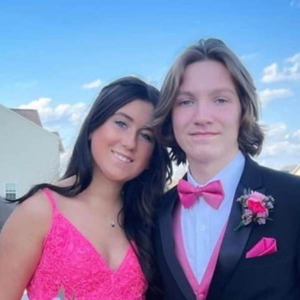 Teen couple in formalwear, one holding a pink and white bouquet