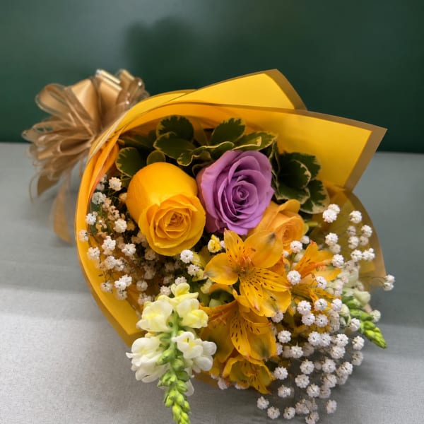 Bouquet of yellow, purple, and orange flowers wrapped in gold paper