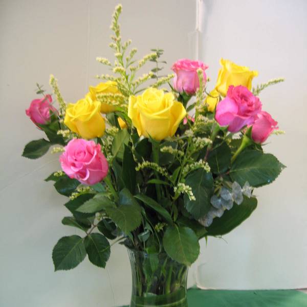 Bouquet of yellow and pink roses in a clear glass vase