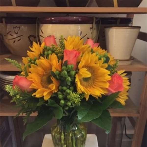 Bouquet of sunflowers and pink roses in a glass vase