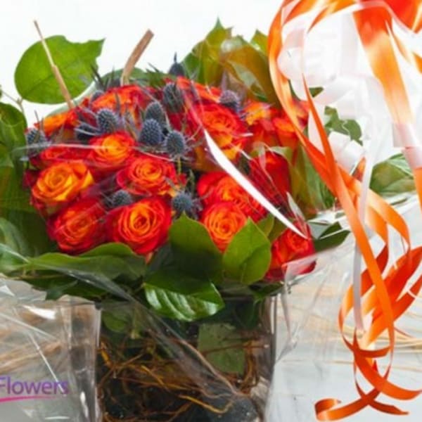 Bouquet of orange-red roses with green leaves and orange ribbon