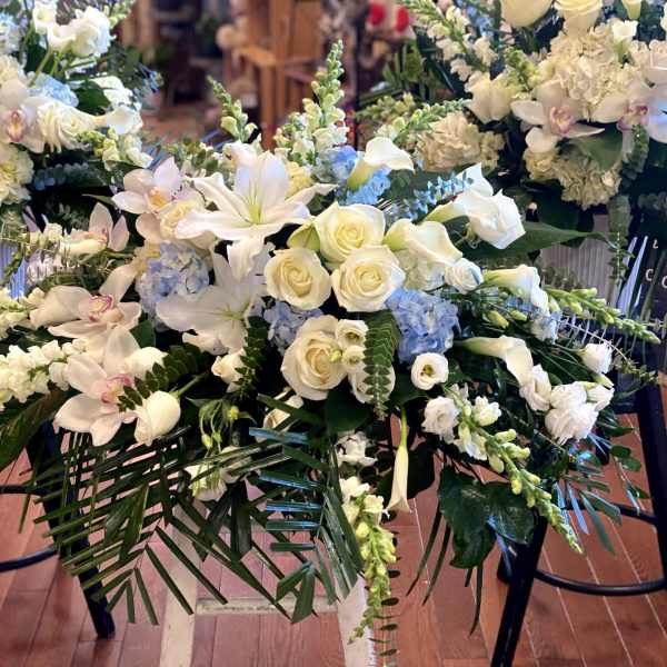 White floral casket spray with roses, lilies, and orchids