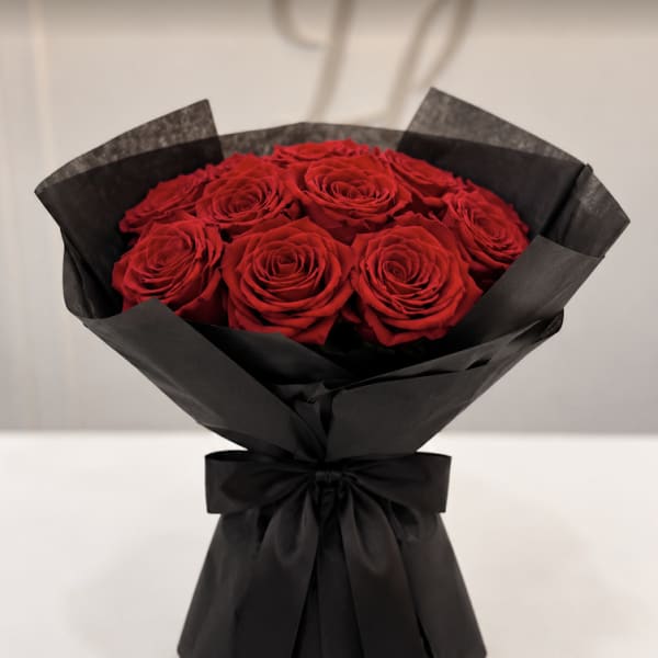 Bouquet of red roses wrapped in black paper with a black ribbon