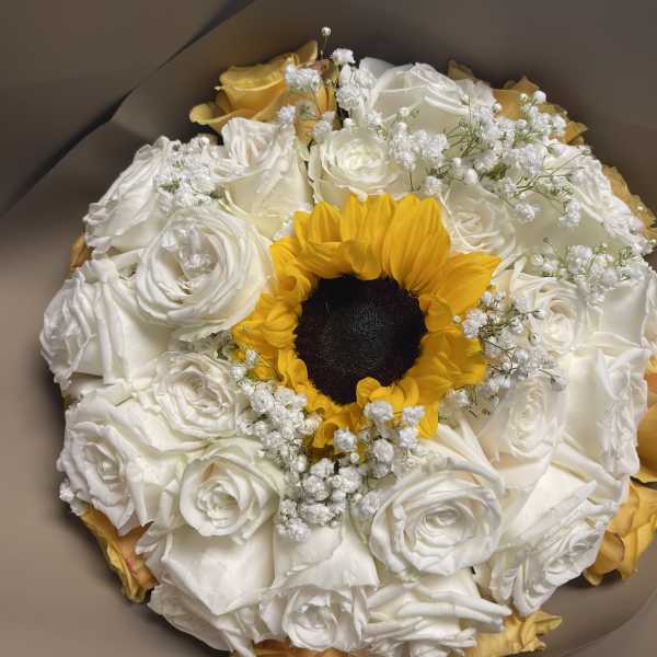 Bouquet of white roses with a yellow sunflower center