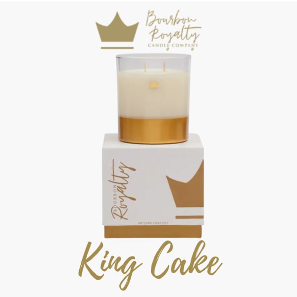 A gold and white candle in a glass jar on a branded box
