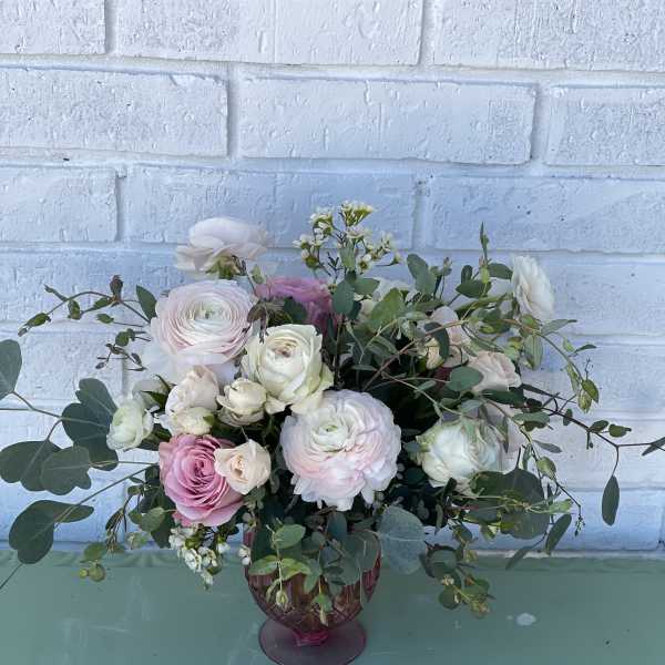 Pink and white roses arranged in a purple glass vase