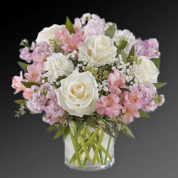 Pink and white bouquet of roses and lilies in a clear glass vase