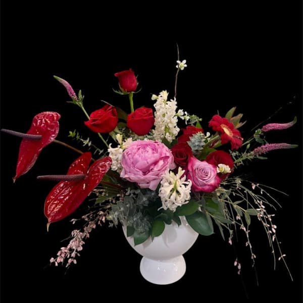 Red and pink floral arrangement in a white vase