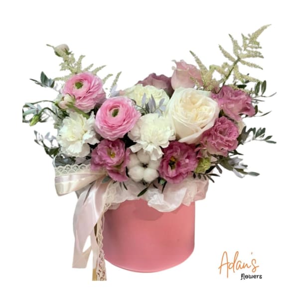 Pink and white flower arrangement in a pink hatbox with ribbon