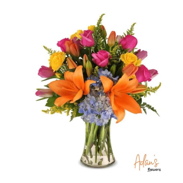 Colorful bouquet of lilies, roses, tulips, and hydrangeas in a glass vase