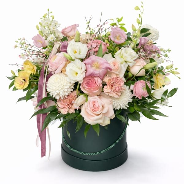 Pastel flower arrangement in a dark round box