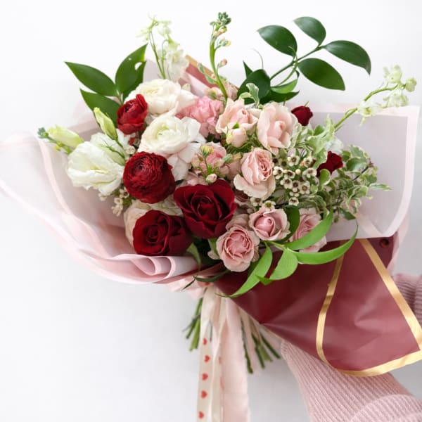 Bouquet of red, pink, and white roses wrapped in pink paper