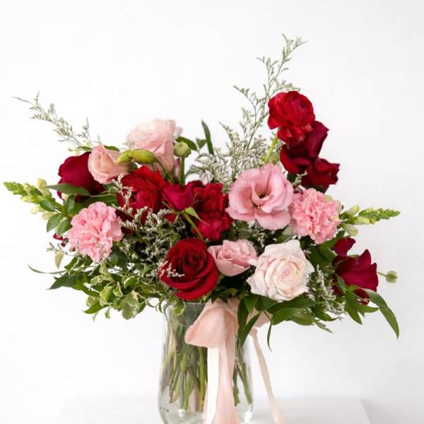 Bouquet of red and pink roses in a glass vase with a pink ribbon