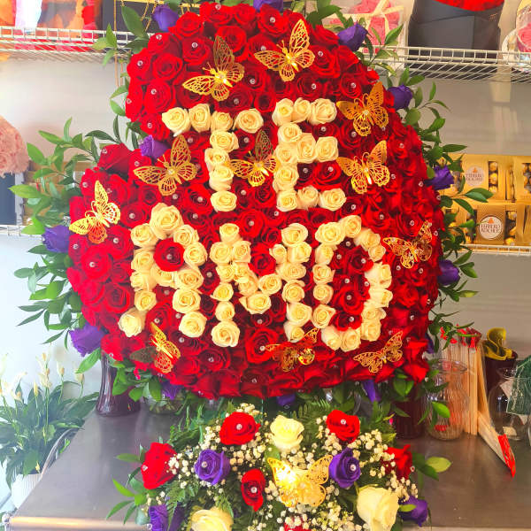 Large heart-shaped rose arrangement with red, cream, and purple roses