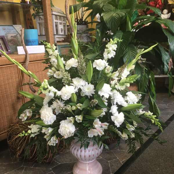 Large white floral arrangement in a pink pedestal vase