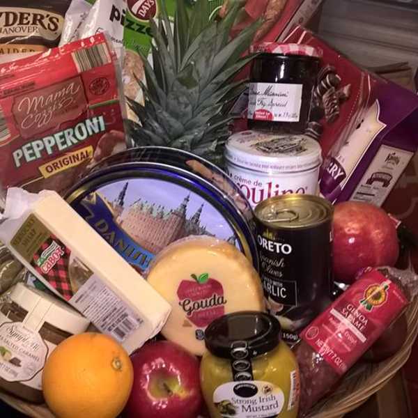 Gift basket with assorted snacks, cheese, fruit, and a pineapple centerpiece