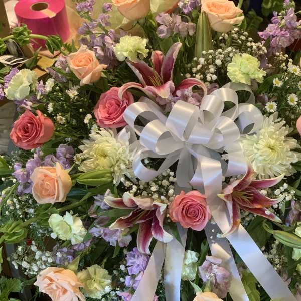Mixed bouquet with roses, lilies, and a white ribbon bow