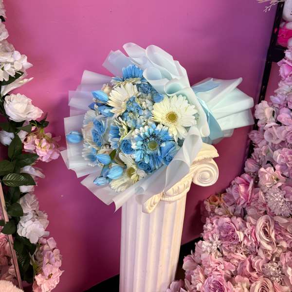 Blue and white bouquet wrapped in translucent paper on a pedestal