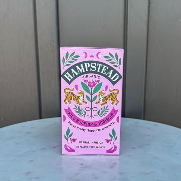 Pink box of Hampstead organic wild rosehip and hibiscus herbal tea on a round table.