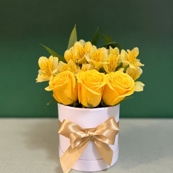 Yellow roses and yellow alstroemeria in a white round box with a gold ribbon