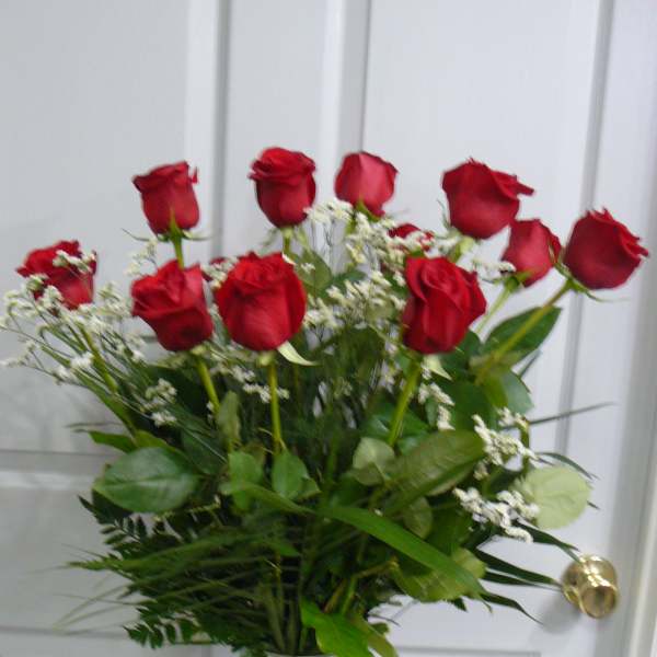 Red roses arranged in a clear glass vase with white filler flowers