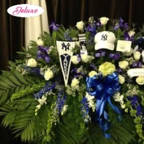 Large funeral spray with white roses, purple flowers, and a blue ribbon