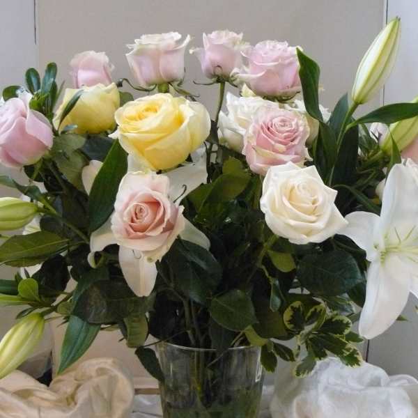 Bouquet of pink and white roses with white lilies in a glass vase