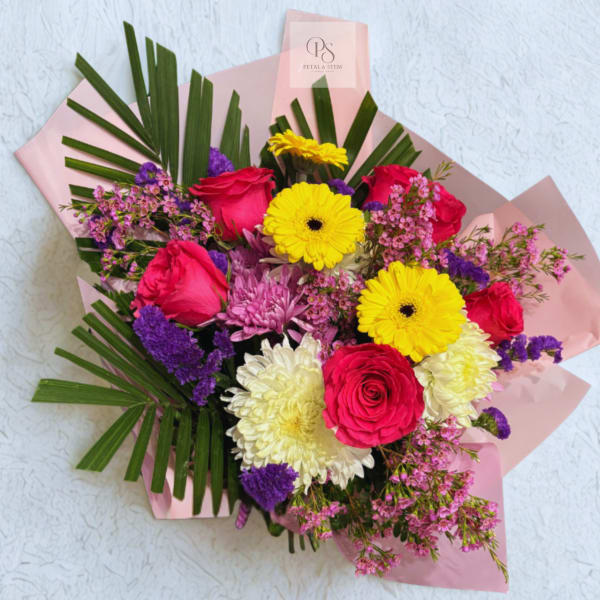 Mixed bouquet of roses, gerbera daisies, and chrysanthemums wrapped in pink paper