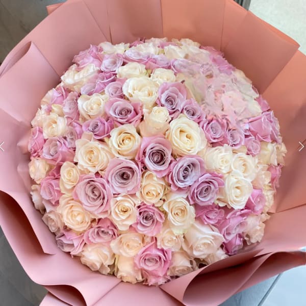 Large bouquet of pink, lavender, and cream roses wrapped in pink paper