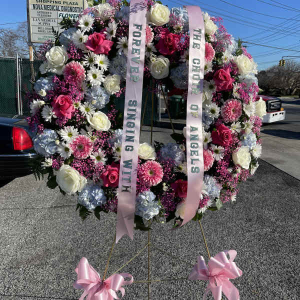 Large floral standing wreath with pink and white flowers and memorial ribbons