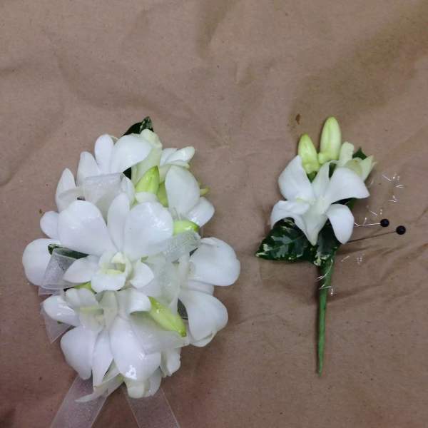 White floral corsage and boutonniere with ribbon accents