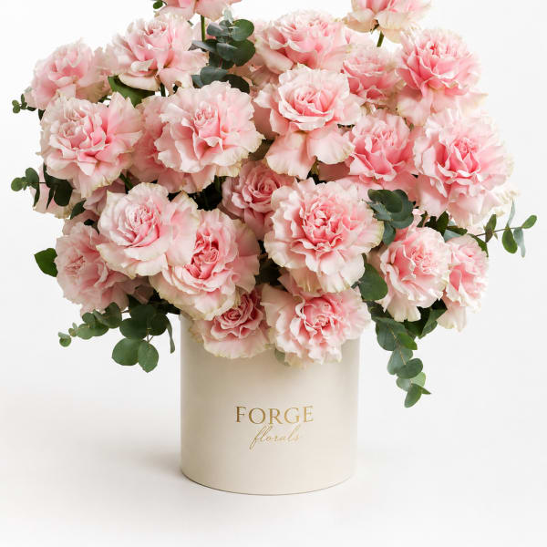 Pink carnations arranged in a cream hat box
