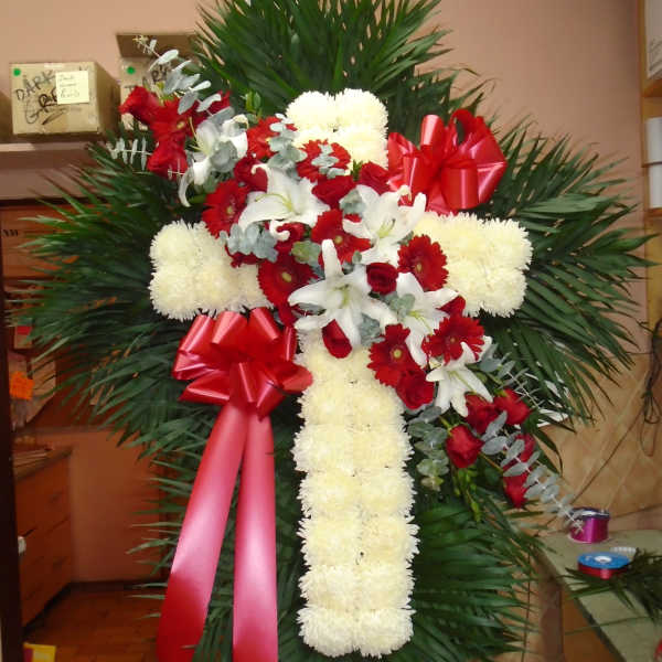 Standing floral cross with red and white flowers and red ribbons