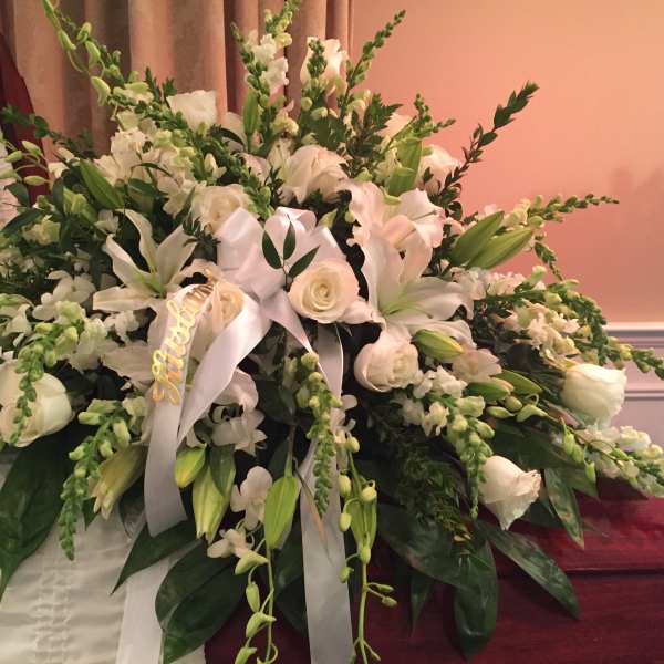 Large white funeral spray with lilies, roses, and ribbon
