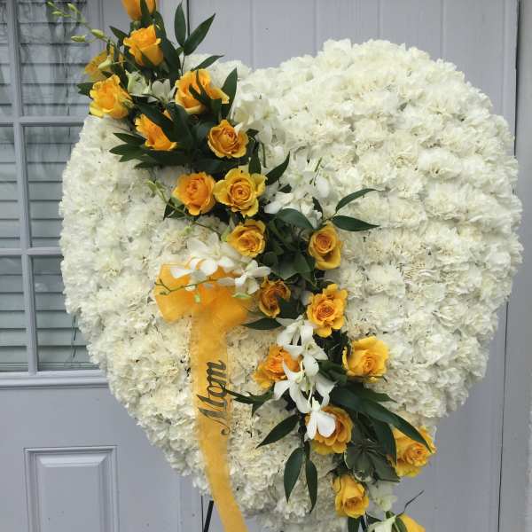 Heart-shaped white floral spray with yellow roses and ribbon
