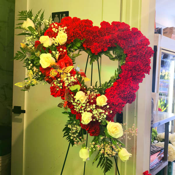Heart-shaped floral standing arrangement with red carnations and yellow roses
