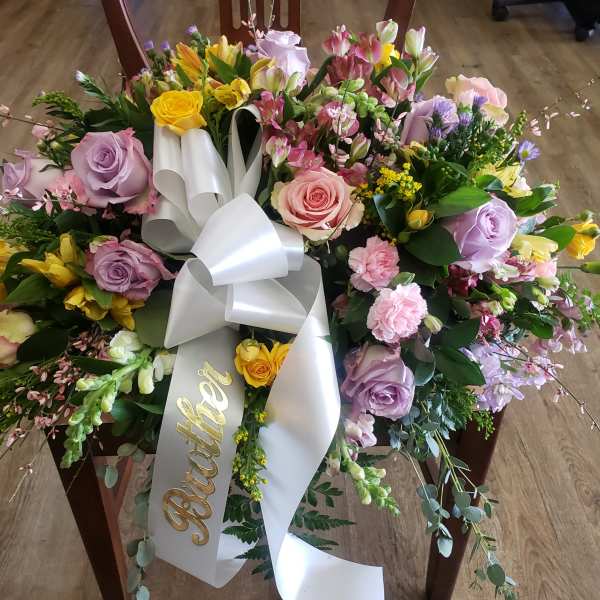 Large floral wreath with pastel roses and a white ribbon bow