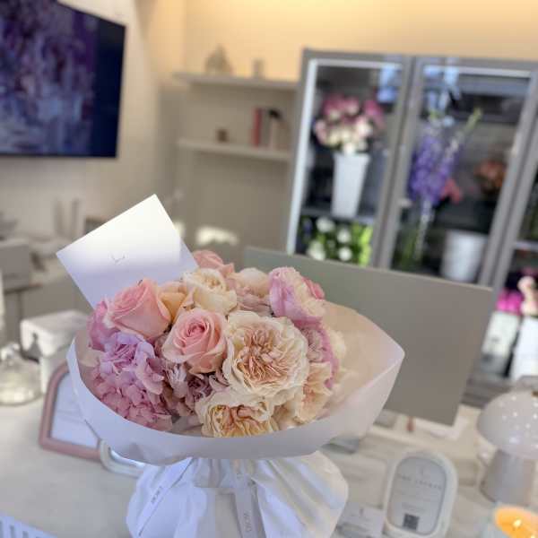 Bouquet of pink and cream roses wrapped in white paper