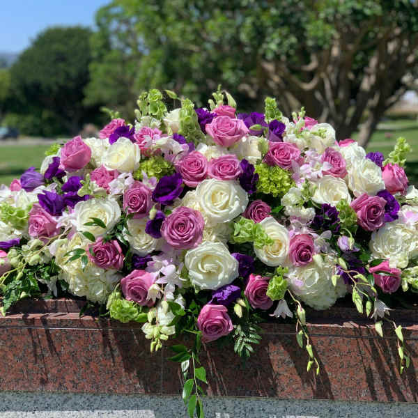 Large arrangement of pink, white, and purple roses on a stone ledge