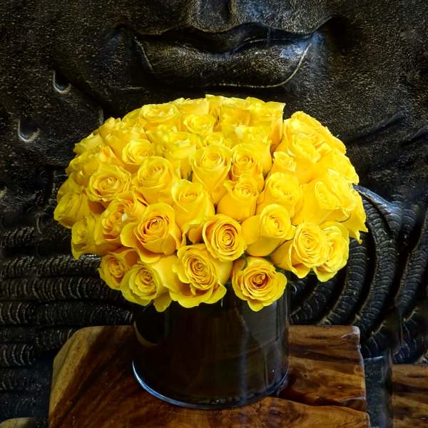 Bouquet of yellow roses in a dark cylindrical vase