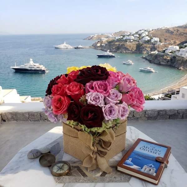 Mixed roses in a burlap-wrapped box on a table overlooking the sea