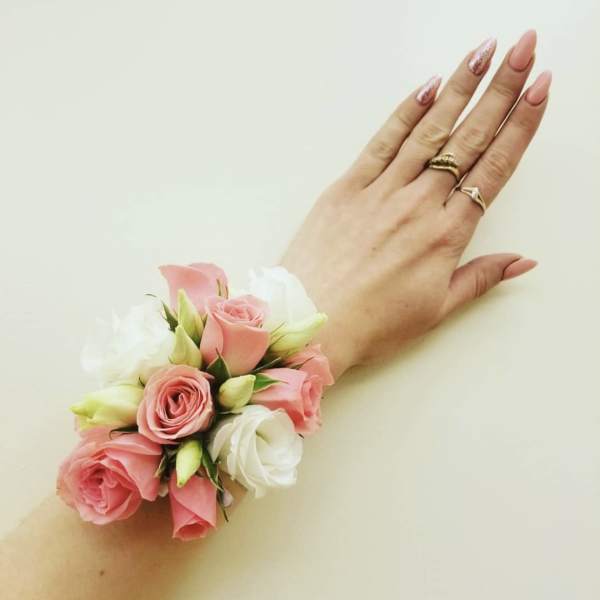 Pink and white rose wrist corsage on a hand