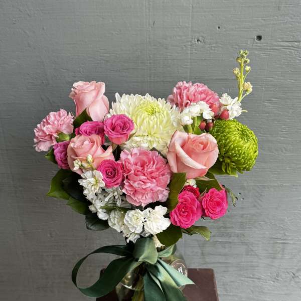 Pink and white mixed bouquet in a glass vase with a green ribbon