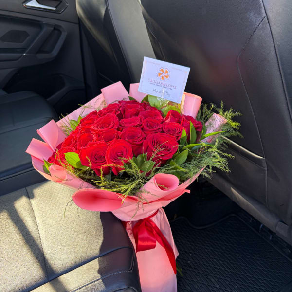 Bouquet of red roses wrapped in pink paper with a red ribbon