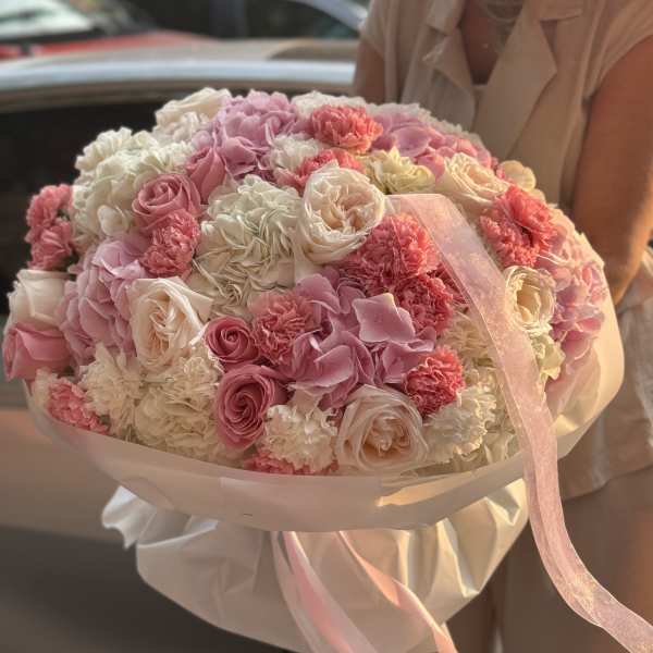 Large bouquet of pink and white roses and carnations wrapped with ribbon