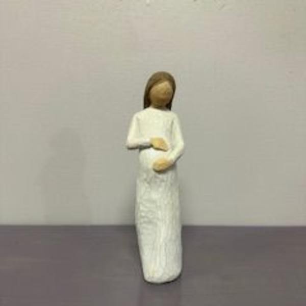 Small angel figurine in a white dress standing on a plain surface