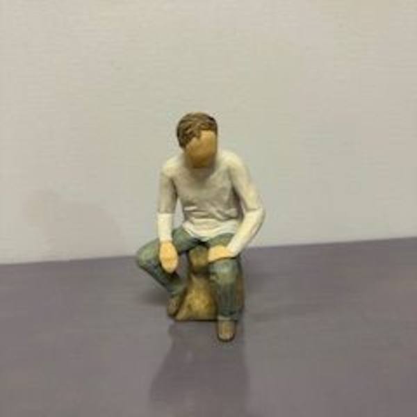Small seated figurine of a person on a stool