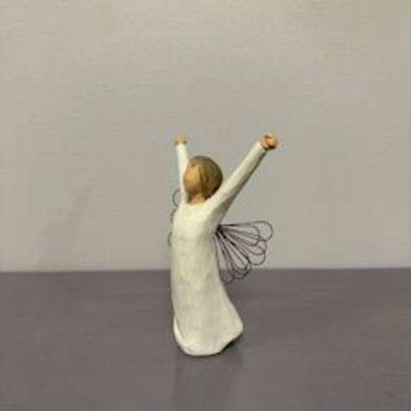 Small angel figurine in a white dress with raised arms