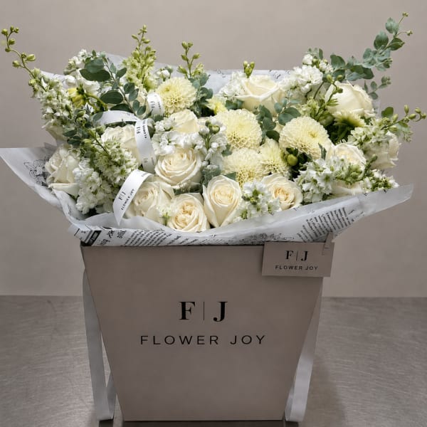 Cream and white bouquet of roses and dahlias in a branded box
