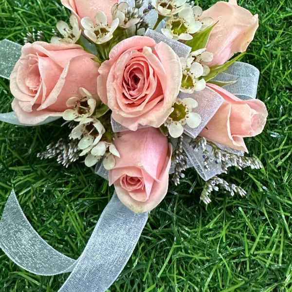 Small pink rose bouquet with white filler flowers and a blue ribbon
